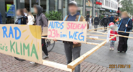 2021.9.19　 市民環境団体「交通転換ライプツィヒ」（Verkehrswende Leipzig）による「歩行車行列」。男性の持つ板には「クルマは23時間止まっている」と書かれ、場所をとる不動産だということを示している。