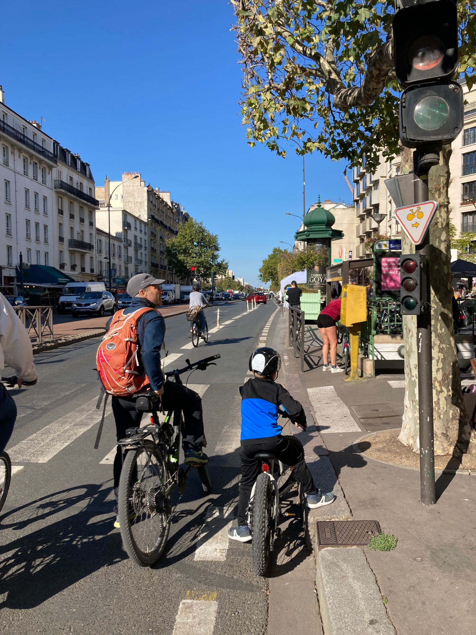 自転車に乗った子どもと大人が信号待ちをしているパリの街かどの写真