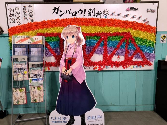 別所温泉駅構内に飾られた折り鶴の橋と、キャラクターの等身大イラストの写真