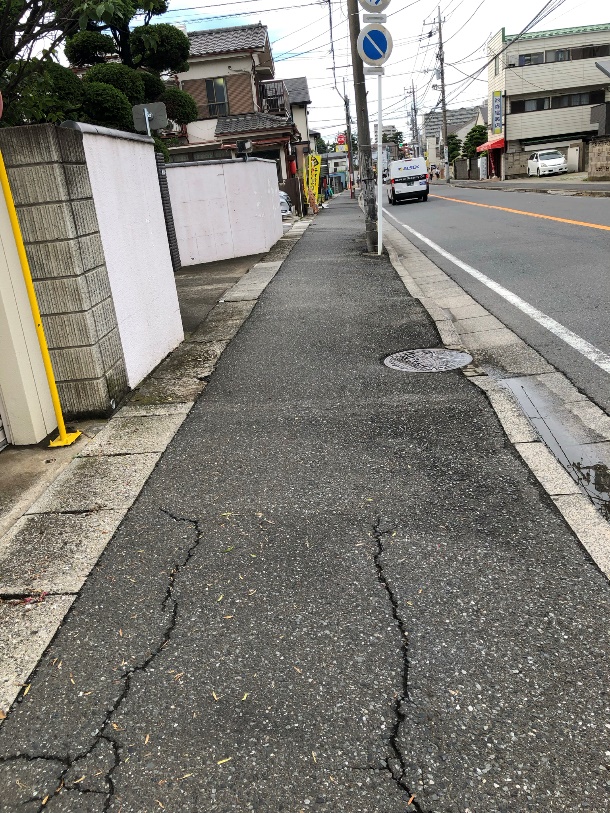 住宅街にある2車線道路の歩道の写真です