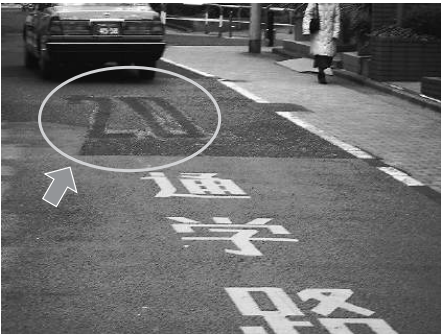 路面に「20」と書かれた文字が消された跡が残る道路の写真です。