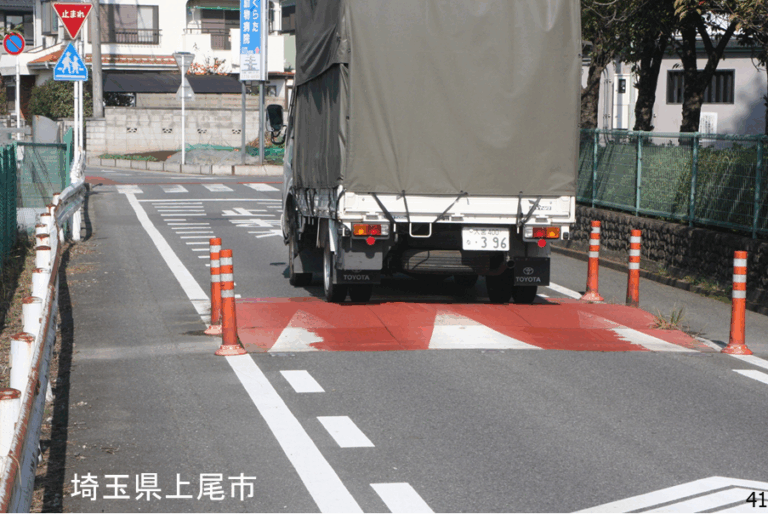 ハンプのある道路をトラックが通っているところの写真です。