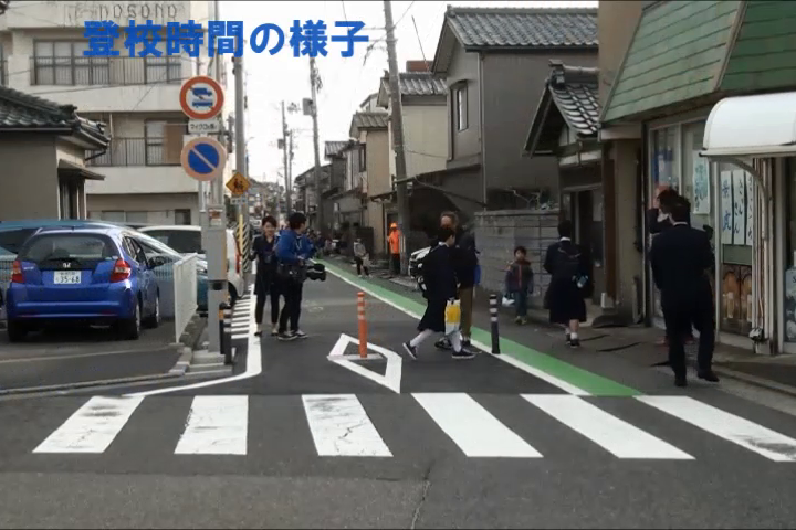 住宅街の道路を歩く生徒たちの写真です。
