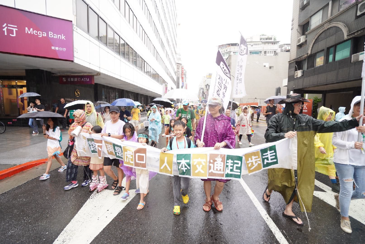 大勢の大人や子どもが横断幕を広げて道路を行進しているところの写真です。