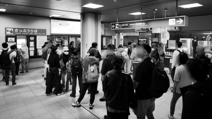 大勢の人が駅内で並んでいるところの写真です。