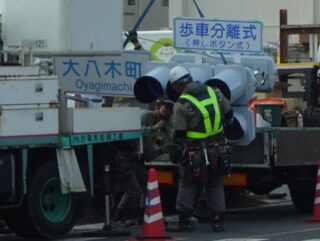 「歩車分体式(押ボタン式)」と標示された信号機を取りつけているところです。