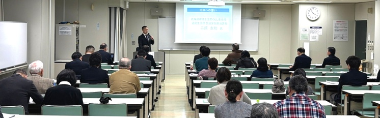 会場で大勢の参加者が熱心に講演を聴いている様子